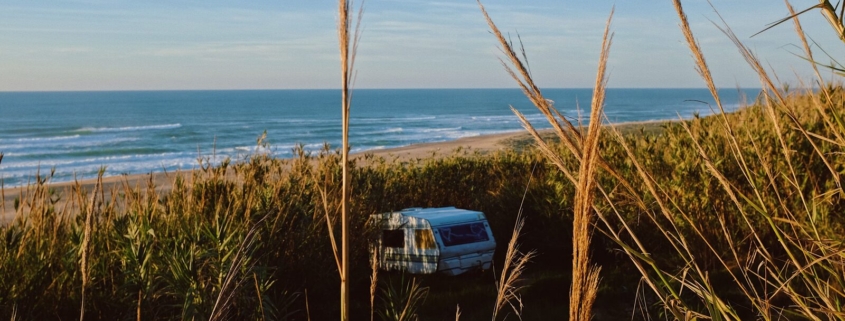 Aire camping-car bord de mer parmi les buissons face à l'océan
