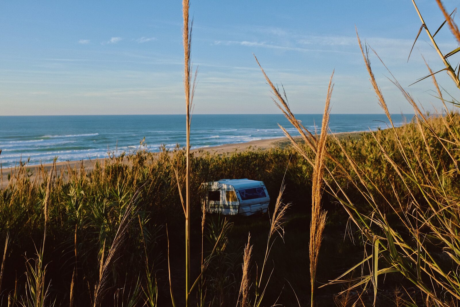 Camping-car installé derrière la dune face à la mer, en fin de journée