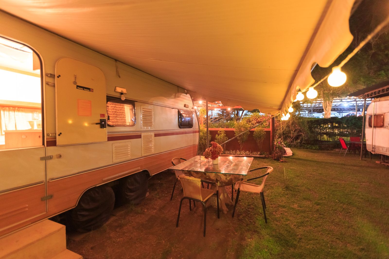 Auvent camping-car déployé et éclairé lors d'une soirée en camping
