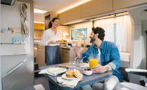 Salon d'un camping-car profilé étroit Adria Compact : table dressée pour un petit-déjeuner