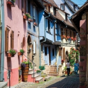 Camping-car en Alsace : ruelle pavee de Riquewihr bordee de maisons a colombages fleuries