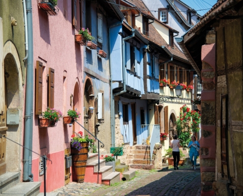 Camping-car en Alsace : ruelle pavee de Riquewihr bordee de maisons a colombages fleuries