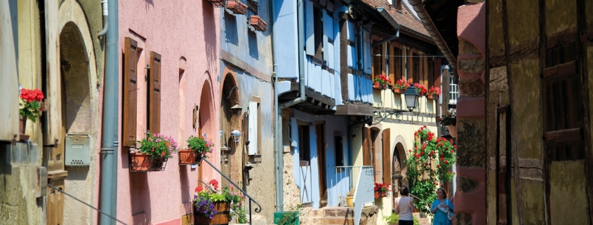 Camping-car en Alsace : ruelle pavee de Riquewihr bordee de maisons a colombages fleuries