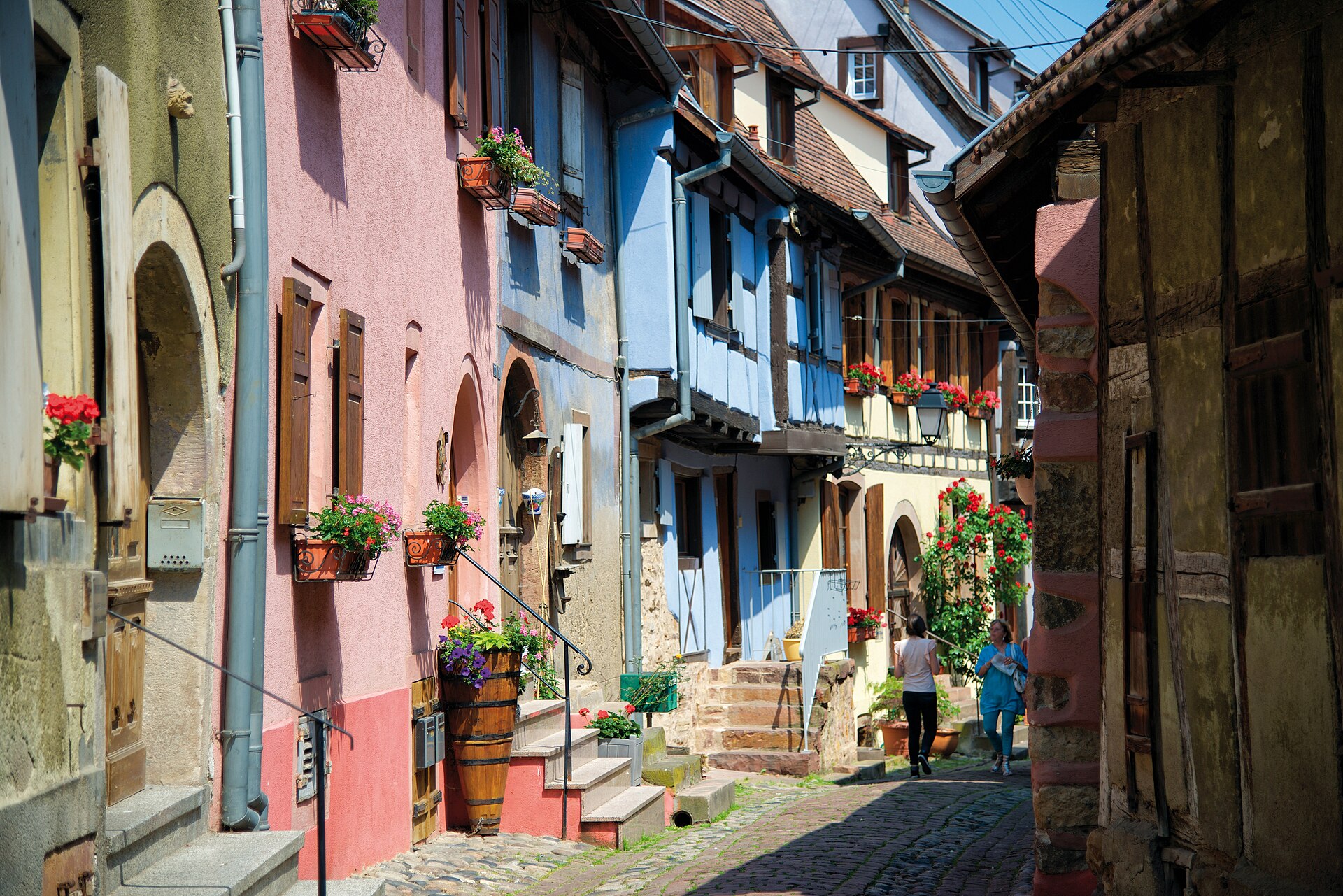 Camping-car en Alsace : ruelle pavee de Riquewihr bordee de maisons a colombages fleuries