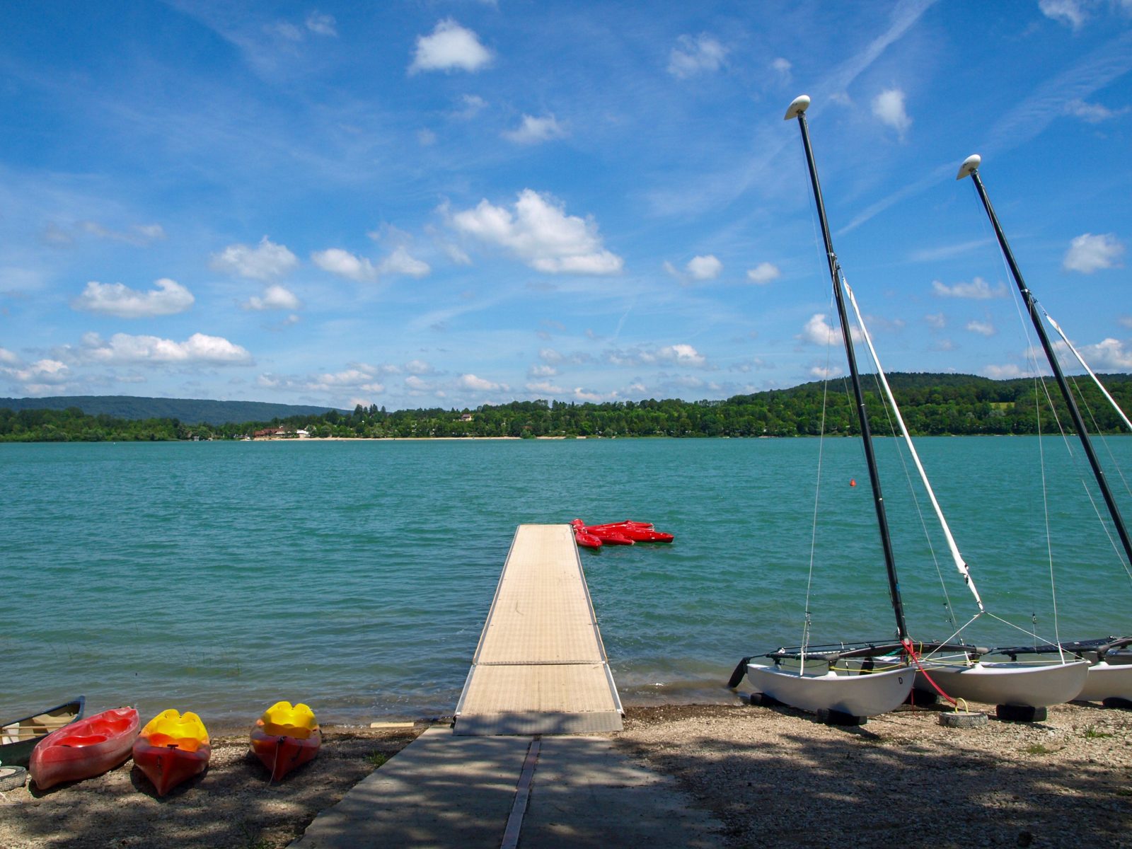 Camping-car garé au bord d'un lac dans le Jura, paysage de forêt en arrière-plan